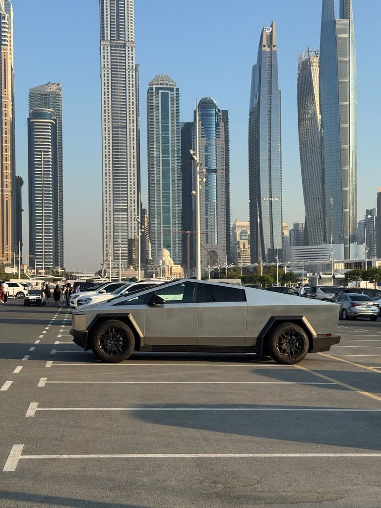 Un Tesla Cybertruck aparcado con el skyline de Dubái al fondo.