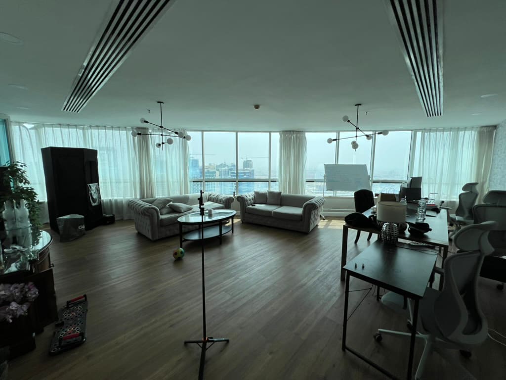 Salón y zona de trabajo de mi piso en Dubái Marina, con dos sofás frente a un ventanal panorámico que da al skyline.